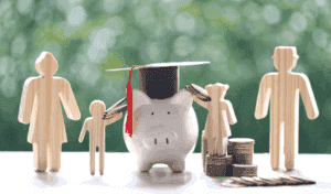 Piggy Bank Surrounded By Figures, With A Mortar Board On Top And Money Scattered Around, Symbolising The Impact Of The Uk Budget On Schools.